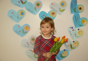 Dziewczynka stoi z bukietem kwiatów dla Babci i Dziadka
